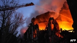 This handout photograph taken and released by the Ukrainian Emergency Service on July 20, 2023 shows rescuers extinguishing a fire at a destroyed residential building after a missile strike in the center of Mykolaiv.