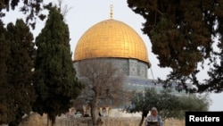 A Palestinian woman reads the holy book of Koran in the compound known to Muslims as the Noble Sanctuary and to Jews as the Temple Mount, in front of the Dome of the Rock, during the first day of Ramadan in Jerusalem's Old City, March 23, 2023. 