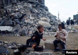 Palestinian children sit by the fire next to the rubble of a house hit in an Israeli strike during the conflict, amid a temporary truce between Hamas and Israel, in Khan Younis in the southern Gaza Strip, Nov. 27, 2023.