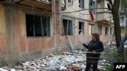 A woman stands near her apartment building damaged in a night attack in the town of Selydove, Donetsk region, on April 14, 2024.