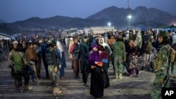 FILE - Taliban fighters stand guard as Afghan refugees wait to register in a camp near the Torkham Pakistan-Afghanistan border in Torkham, Afghanistan, Nov. 4, 2023. 