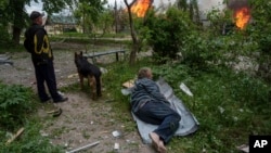 A man lies on the ground as he watches his burning home, destroyed by a Russian airstrike in Vovchansk, Ukraine, May 11, 2024.