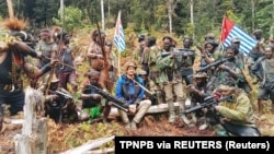 Pria yang diidentifikasi sebagai Philip Mehrtens, pilot Susi Air berkebangsaan Selandia Baru yang disandera kelompok separatis, tampak duduk bersama para kombatan di Papua, 6 Maret 2023. (Foto: TPNPB via REUTERS)