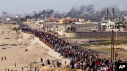 Palestinians wait for aid trucks to cross in central Gaza Strip on May 19, 2024. 