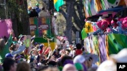 Orang-orang berebut manik-manik yang dibagikan saat parade Krewe of Iris Mardi Gras di New Orleans, 18 Februari 2023. (AP/Gerald Herbert)