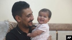 Khalil al-Sawadi plays with his adopted daughter Afraa in Jinderis, Syria, on Aug. 5, 2023. Afraa was born under the rubble of her family home, destroyed by the deadly earthquake that hit Turkey and Syria six months ago, killing her parents and siblings.