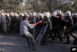 A supporter of former Prime Minister Imran Khan's party scuffles with riot police officers outside Khan's residence, in Lahore, Pakistan, March 14, 2023.