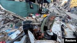 A Palestinian woman prepares a meal amid the rubble of her home, which was destroyed during Israel's military offensive, in Beit Lahia, northern Gaza Strip, March 13, 2024.