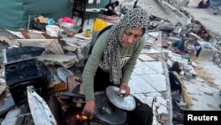 উত্তর গাজা ভূখণ্ডের বেইত লাহিয়া এলাকায় ইসরাইলি হামলায় এক ফিলিস্তিনি নারীর বাড়ি ধ্বংস হওয়ার পর ভাঙা পাথরের মাঝে তিনি রান্না করার চেষ্টা চালাচ্ছেন। (১৩ মার্চ, ২০২৪)