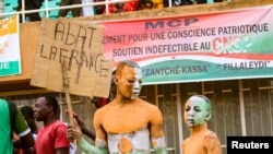 FILE - A supporter of Niger's coup leaders holds a sign reading "Knock down France" during a rally at a stadium in Niamey, Niger, Aug. 6, 2023. 
