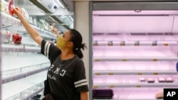 A woman selects products near empty shelves at a supermarket as Super Typhoon Saola approaches Hong Kong on Sept. 1, 2023. 