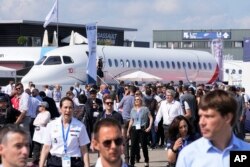FILE - Visitors walk by a Falcon 10X prototype by the French manufacturer Dassault Aviation, at the Paris Air Show, June 21, 2023 in Le Bourget, north of Paris. Airlines are facing increasing pressure to cut their climate-changing emissions.