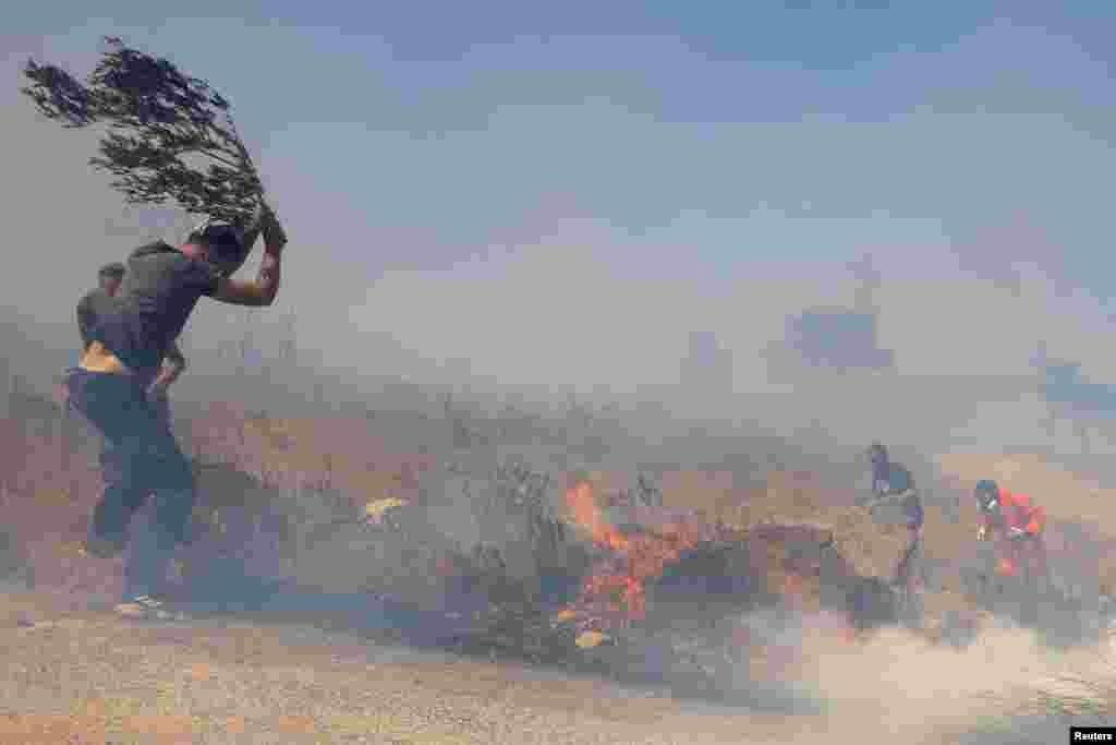 A firefighter and local residents extinguish a wildfire burning in Keratea, near Athens, Greece.