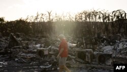 A resident looks around a charred apartment complex in the aftermath of a wildfire in Lahaina, western Maui, Hawaii, Aug. 12, 2023.