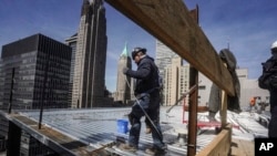 FILE - Construction workers install roofing on a high rise in Manhattan's financial district on April 11, 2023, in New York. 