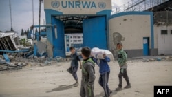Children carry bags of flour after humanitarian aid was distributed in Gaza City on March 17, 2024. 