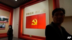 FILE - Visitors stand near a flag of the Chinese Communist Party at an exhibition in Shanghai, April 20, 2023. Foreign investment in China fell for the 12th consecutive month in May, according to China’s Ministry of Commerce.   