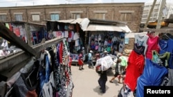 FILE - A worker carries a bale of imported second-hand clothes past displayed apparel at the Gikomba market in Nairobi, Kenya, Sept. 18, 2020.