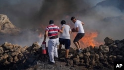 FILE - Local residents try to extinguish a fire, near the seaside resort of Lindos, on the Aegean Sea island of Rhodes, southeastern Greece, on July 24, 2023.