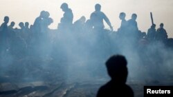Warga Palestina mencari makanan di antara puing-puing yang terbakar pasca serangan Israel di daerah yang diperuntukkan bagi para pengungsi, di Rafah di selatan Jalur Gaza, 27 Mei 2024. (Foto: REUTERS/Mohammed Salem)