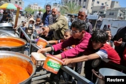 Palestinians gather to receive food cooked by a charity kitchen, amid shortages of aid supplies, after Israeli forces launched a ground and air operation in the eastern part of Rafah in the southern Gaza Strip, May 8, 2024.