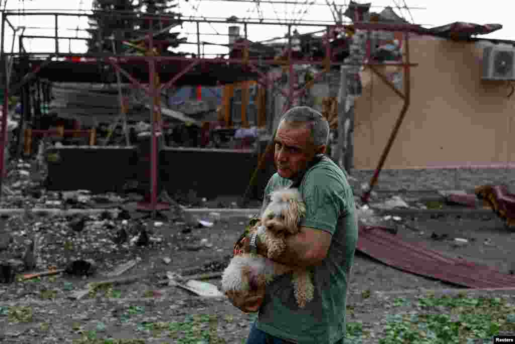 Vahe Ohandzanian, de 54 años, sostiene un perro junto a su café gravemente dañado por el ataque aéreo ruso en Járkov, Ucrania, el 22 de mayo de 2024. REUTERS/Valentyn Ogirenko