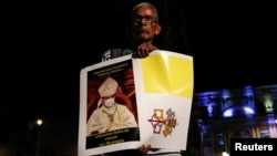 FILE - A Nicaraguan exiled in Costa Rica holds a poster with a Vatican City flag during a protest against the detention of Bishop Rolando Alvarez by Nicaraguan authorities, outside the Metropolitan Cathedral in San Jose, Costa Rica, Aug. 19, 2022.