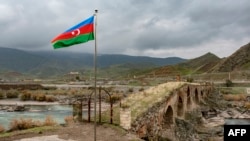 FILE - An Azerbaijani national flag flies next to the mediaeval Khudaferin bridge in Jebrayil district at the country's border with Iran, Dec. 9, 2020.