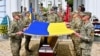 Ukrainian soldiers hold a Ukrainian national flag to cover the coffin of U.S. volunteer Christopher James Campbell during his funeral ceremony outside of the Mykhaylo Golden Domes cathedral in Kyiv on May 5, 2023. (Sergei Supinsky/AFP)