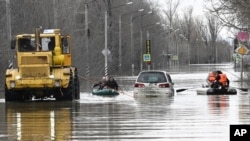 People use rubber boats in a flooded street in Orsk, Orenburg region, Russia, April 7, 2024. (Anatoly Zhdanov/Kommersant Publishing House via AP)