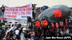 Para pedemo mengusung orang-orangan Presiden Filipina Ferdinand Marcos Jr dan mantan presiden Rodrigo Duterte dalam pawai peringatan ke-37 tahun revolusi "People Power" yang menggulingkan ayah Presiden Marcos Jr, di Quezon City, Sabtu, 25 Februari 2023. (Foto: Jam Sta Rosa/AFP)