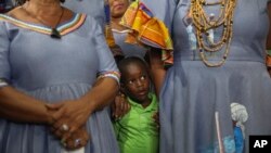 A child stands with Vodou pilgrims during a Mass marking the feast day of agriculture and work, in Port-au-Prince, Haiti, May 1, 2024.