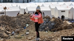 A girl holding sports balls stands at a camp for survivors, in the aftermath of the deadly earthquake, in Adiyaman, Turkey, Feb. 18, 2023.