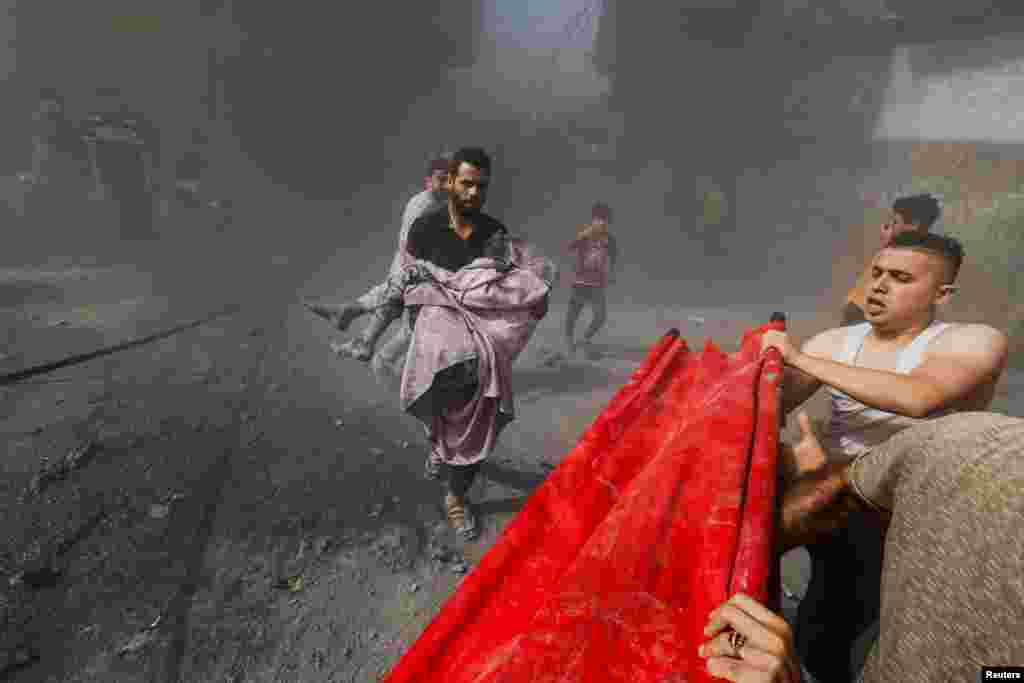 A Palestinian man carries a child casualty at the site of Israeli strikes on houses, as the conflict between Israel and Palestinian Islamist group Hamas continues, in Khan Younis in the southern Gaza Strip.