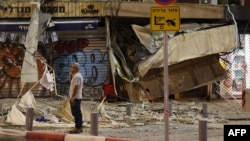 A man stands in front of a damaged shop in Tel Aviv, after it was hit by a rocket fired by Palestinian militants from the Gaza Strip, Oct. 7, 2023.