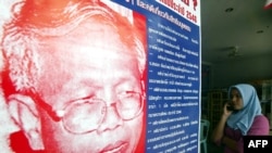 FILE - A woman looks at a poster of lawyer Somchai Neelapaijit who disappeared in front of a mosque in Pattani province on March 30, 2004, following violence in the south of Thailand.