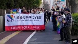 FILE - Activists carry a banner in support of same-sex marriage as supporters wave rainbow flags in Tokyo on March 14, 2024. The Nagoya High Court ruled on March 7, 2025, that not allowing same-sex couples the legal right to marry violates a constitutional guarantee of equality.