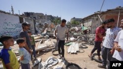 Palestinians salvage items from the rubble of the al-Madhoun family home following overnight Israeli strikes in the Nuseirat refugee camp in the central Gaza Strip, on June 18, 2024.