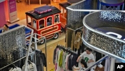 FILE - Women and their children ride on a miniature train passing shoppers at a mall in Beijing, Aug. 20, 2023. Chinese leader Xi Jinping recently called for patience in a speech as the ruling Communist Party tries to reverse a deepening economic slump.