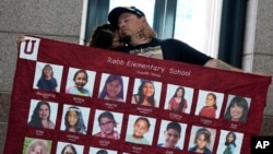 FILE - Abel Lopez, right, father of Xavier Lopez who was killed in the shootings in Uvalde, Texas, holds a banner honoring the victims, in Austin, Texas, May 8, 2023.