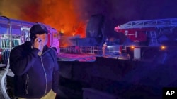 The Governor of Sevastopol, Mikhail Razvozhaev, is seen speaking on a phone as smoke and flame rise from a burning shipyard in Crimea in this photo posted to Razvozhaev's Telegram channel on Sept. 13, 2023.