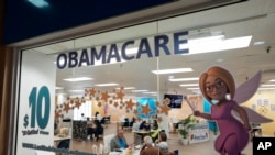 FILE - An insurance agent talks with clients inside the main location of Las Madrinas de los Seguros, Spanish for "The Godmothers of Insurance," at a shopping center in Miami, on Dec. 5, 2023. 