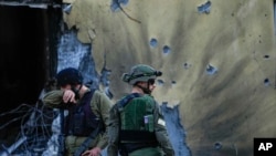 Soldados israelíes pasan junto a casas destruidas por militantes de Hamas en el Kibbutz Be'eri, Israel, el sábado 14 de octubre de 2023.