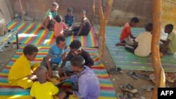 Children share a large bowl of food, as Sudanese families host internally displaced people coming from the central Sudanese state of Gezira to the eastern Sudanese city of Gedaref, June 3, 2024.