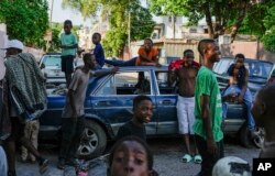 Young people hang out near cars serving as street barricades placed there by residents to deter gangs from entering their neighborhood, in downtown Port-au-Prince, on May 17, 2024. (Ramon Espinosa/AP)