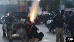 FILE - Police fire tear gas shells towards Pakistan Tehreek-e-Insaf (PTI) party activists and supporters of Pakistan's former prime minister Imran Khan during a protest against the arrest of their leader, in Karachi, May 9, 2023.