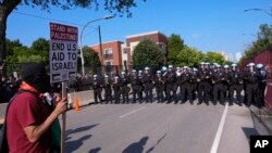 Police walk towards protesters who knock down a fence surrounding United Center at the Democratic National Convention after a march, Aug. 19, 2024, in Chicago.