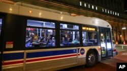 FILE - Migrants wave as a bus leaves to take them to a refugee center outside Union Station in Chicago, Aug. 31, 2022.