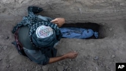 An Afghan man buries his grandson who was killed by the earthquake in the Zindajan district of the Herat province of Afghanistan, Oct. 9, 2023. The earthquake, which struck two days earlier, killed and injured thousands.