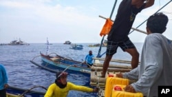 In this photo provided by Atin-Ito/Akbayan Party, activists and crew members distribute fuel to fishermen in the South China Sea, May 15, 2024. 